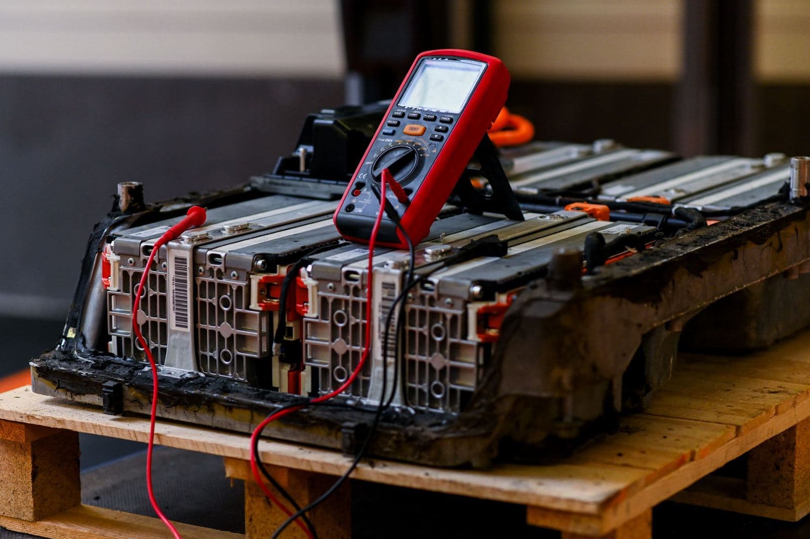 Een multimeter op een geopend hybride accupakket, met meetsnoeren aan de modules.