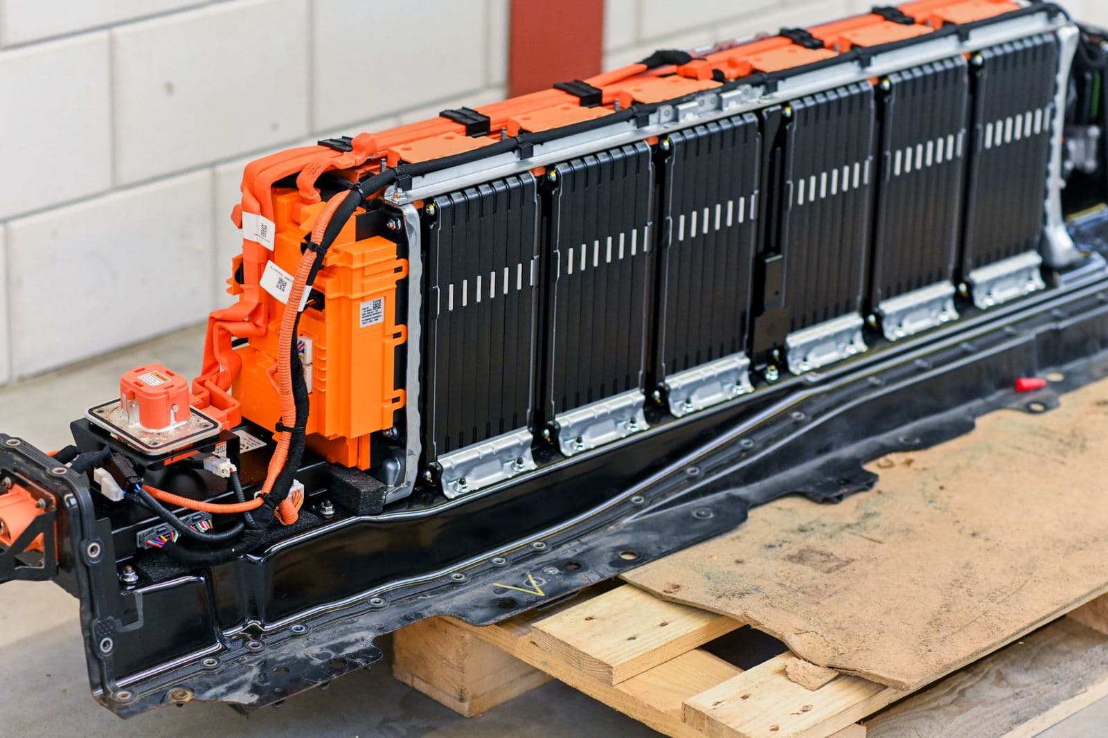 Een groot plug-in hybride accupakket met oranje hoogvoltaansluitingen op een pallet.