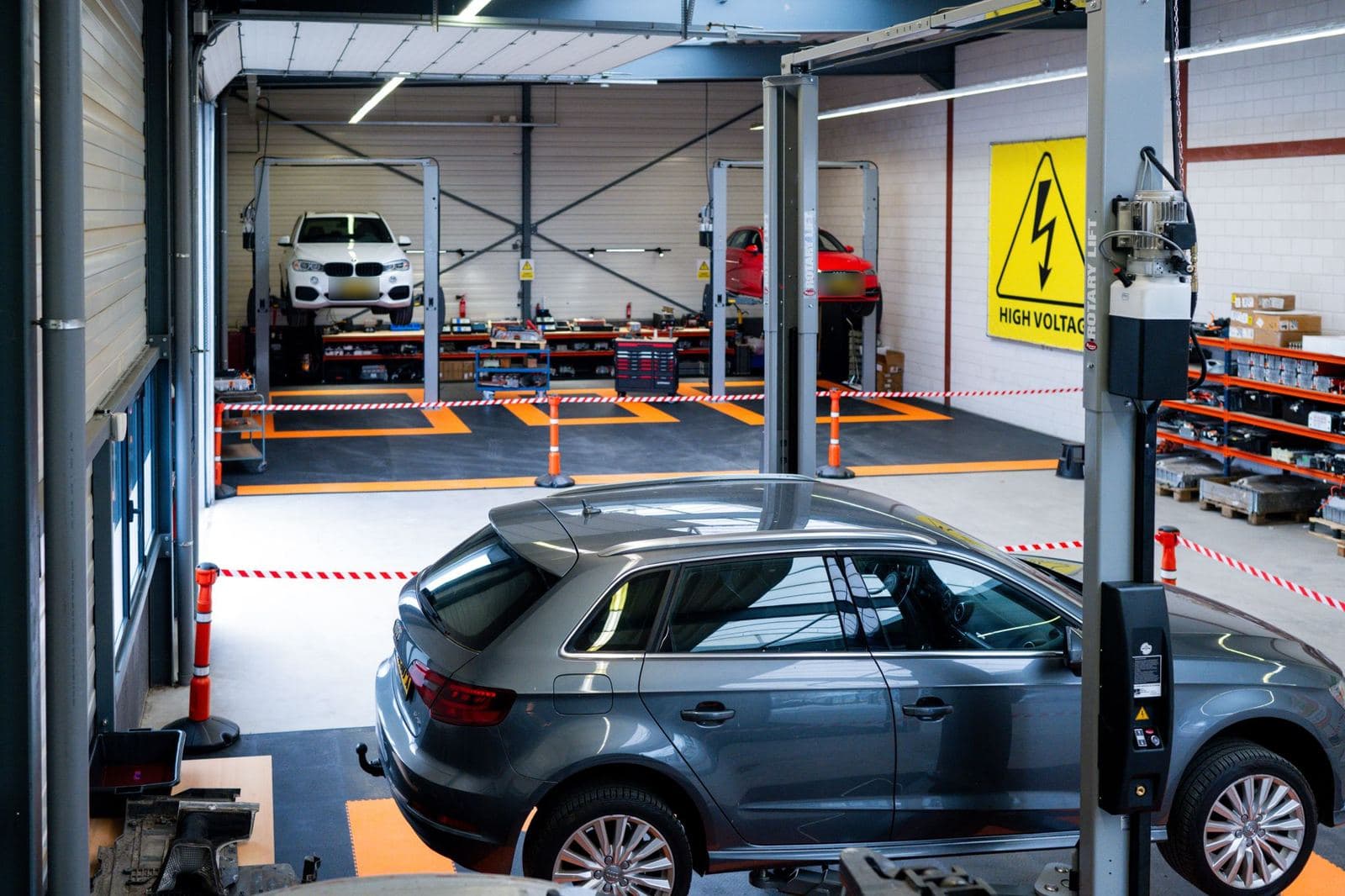 De werkplaatshal aan de Kleine Krogt met twee bruggen, oranje vloermarkering en een auto op de voorgrond.